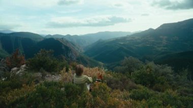 Woman and dog on top of mountain look at breathtaking view. Genuine outdoor lifestyle, travel with dog. Autumn vacation in Europe.