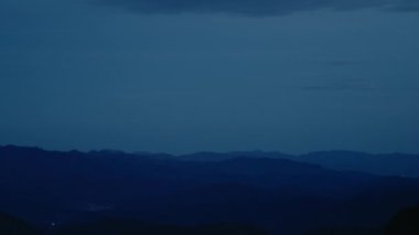 Landscape scenery of dusk sunset in mountains. Majestic blue sky and clouds over beautiful tops of the hills. Dramatic sunset or sunrise moment 