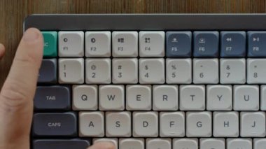 Top view of retro style computer keyboard on the wooden table. Male hand repeatedly click escape green button. Freelancer or office manager finishing work. 
