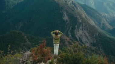 Mountain Hill 'in tepesinde geleneksel süveter giyen sinematik kadın Forest Valley' e bakıyor. Genç yürüyüşçü açık hava yaşam tarzını seviyor. Doğanın haşmeti. Seyahat kavramı.