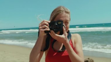 Kadın turist fotoğrafçısı Leica 'nın kamerasında fotoğraf çekiyor. Plajın altın kumları berrak denizle buluşur, yazın özünü yakalar..