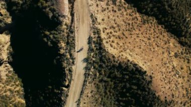 Profesyonel kadın bisikletçi çölde meydan okuyor, çakıllı bisiklete manzaralı bir şekilde biniyor. Macera egzersizleri huzurlu bir kaçış ve seyahat tutkusu hissi sunar. Üst görünüm. 