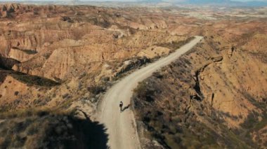 Dişi bisikletçi çölün güzelliklerini keşfeder, çakıl taşları üzerinde bisikletini sürerek nefes kesici manzarayı seyreder. Açık hava macerası barışçıl bir kaçış ve doğada ferahlatıcı bir egzersiz sağlar..