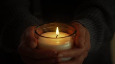 Ellerinde mumla, kadın meditasyon yapar ve dua eder, titreyen alevlerde huzur bulur. Ruhani ayin ona anların kutsal önemini hatırlatıyor. Alev havada dans eder. Falcı.. 