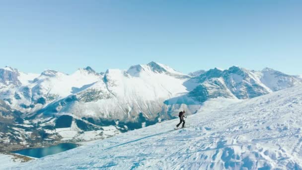 在挪威峡湾风景中 一个滑雪者爬上陡峭的高山 侧拍滑雪者爬山的史诗背景 读起来像滑雪粉降下来 — 图库视频影像