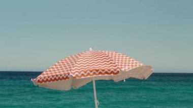 Sinema kırmızı ve beyaz plaj şemsiyesi rüzgarda savruluyor. Yaz tatili konsepti. Idyllic ve basit tatil cenneti