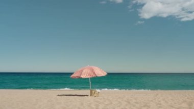 Güneşli şemsiyeli ve dokuma çantalı, cennet gibi boş bir kumsalın sinema minimalistik görüntüsü. Huzurlu ve sakin yaz tatili konsepti. Tatil hedefi
