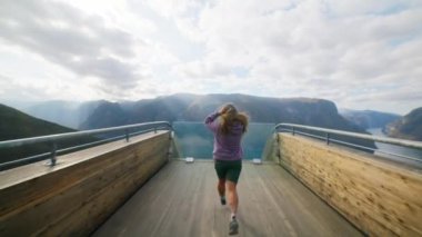 Kameranın sinematik yolculuk görüntüsü genç kadını uçurumun kenarına kadar takip et ve bak. Seyahat blogcusu ve içerik yaratıcısı yeni ülke Norveç 'i keşfetti