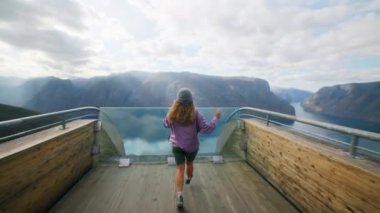 Mutlu, heyecanlı genç bir kadın, seyahat blogcusu Norveç 'te inanılmaz asılı köprü manzarasıyla koşuyor. Sosyal medya etkileyicisi içerik oluşturur. Özgür ve genç turistler iyi yolculuklar. 