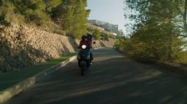 Altea, İspanya - Mayıs 2021. İki kız arkadaş, dağlarda ve yeşil kırsal bölgelerde dolanarak, pitoresk bir yolda motosiklete biniyor. Avrupa 'da sıcak yaz günbatımı. Hedef konsepte ulaşılıyor. 