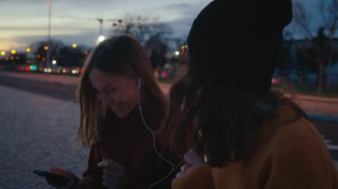 En iyi iki bayan arkadaş gün batımında parkta takılır, müzik dinler ve ritimle dans ederler. Müzik yayın platformu ya da uygulama, iki kadın kulaklıkları paylaşıyor ve eğleniyor, gülümsüyor ve gülüyor. 