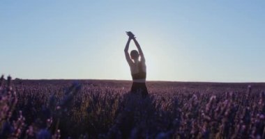 Sporda özgür ve mutlu bir kadın, güneş doğarken lavanta tarlalarında yoga ve asanas giyer. Uygulamanın rüya gibi ve ilham verici doğası. Meditasyonal egzersiz rutini her blog yazarı veya model için mükemmeldir..