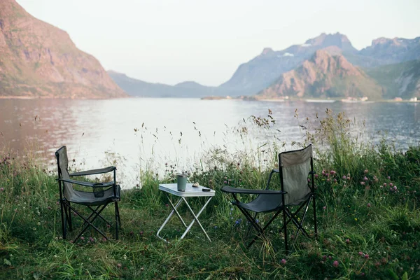 在挪威罗浮敦史诗般的风景中 两张空的折叠式露营椅和海滩上的小桌子 斯堪的纳维亚的电影流浪野营或野营面包车度假概念 — 图库照片