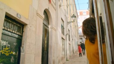 Portekiz 'in başkenti Lizbon' da eski bir tramvayın camından sarkan güzel ve otantik genç bir kadın. Avrupa 'nın muhteşem yaz tatili kavramları, şehirli sinemada gezinti.