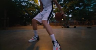 Akşamları iki basketbolcunun park sahasında oynamalarının düşük açılı çekimi. Maçı ya da yarışmayı kazanmak için top sürün ve saha savunması yapın. İşten sonra sokak basketbolu