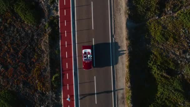 空中トップダウンのドローンは 低夜の太陽の光の中で空の小さな道路上のヴィンテージ古いアメリカの筋肉転換赤い車のドライブのショット 成功した現代生活 — ストック動画
