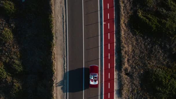 空の新しい沿岸道路 小さな赤いコンバーチブルカーのドライブソロの上の空中ドローンビュー 成功した男 赤いカブリオレのヴィンテージの筋肉車の中のドライバーは日没に乗ります コピースペース — ストック動画