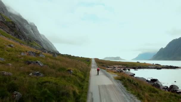 Drone Shot Rowerzysty Jasnoczerwonej Kurtce Jazdy Zacisznej Drodze Żwirowej Norwegii — Wideo stockowe