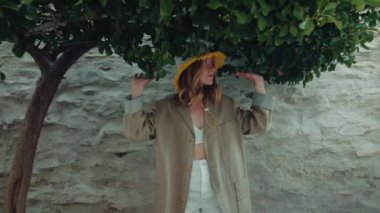 Otantik ve doğal bir manken sokak fotoğrafı çekilirken kameraya gülüp gülümser. Mutlu gülümseyen genç kadın kamerayla flört ediyor ve etkileşime geçiyor.