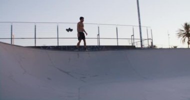 Formda olmayan kaykaycı, gün batımında kaykay kasesinde yüzüyor. Yavaş çekim, kaykay yaşam tarzının özünü ve özgürlük duygusunu yansıtıyor.. 