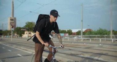Sırt çantalı genç bir adam, bisiklet yolu boyunca bisiklet sürüyor. Ofis çalışanı ya da öğrenci iş ya da okul için acele ediyor. Bisiklet sürme ve yeşil yaşam tarzı tanıtım. 