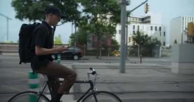 Bisikletli yolcunun bisiklet sürüşünün yan görüntüsü, mesaj göndermek için akıllı telefonuna bak ya da gideceği yeri kontrol et. Yeşil ulaşım ve kentsel taşıma günlük bazda.