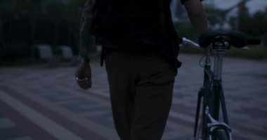 Şık bir genç adam yaya bölgesinde bisikletle yürüyor. Bisiklet meraklıları metro ya da tren istasyonuna gitmek için işe gidip geliyorlar. Sağlıklı şehir ulaşım seçeneği.