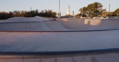 Sıcak bir yaz akşamında üstsüz profesyonel patenci havuz içinde numaralar yapar. Otantik spor konsepti. Günbatımında kaykay kasesinde akıntıyla giden bir genç.. 