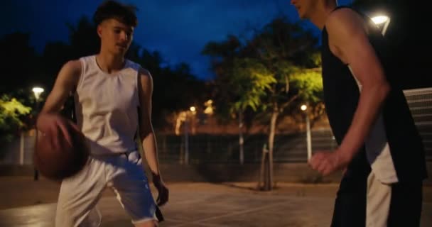 到了晚上 两个流氓在街上打了场打篮球 队友或竞争对手在室外场地的街头篮球赛中竞争 — 图库视频影像