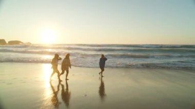 Kaliforniya 'nın kumlu sahillerinde üç mutlu kadının okyanus dalgalarından kaçtığı bu karamsar, ılık yaz çekimlerinde gün batımı titreşimleri.. 