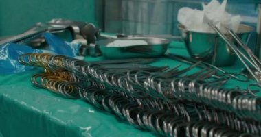 Ameliyat odasındaki ameliyat masasında hazırlanmış farklı sterilize cerrahi aletlerin yakın çekim görüntüleri. Allis, babcock, dunhill ve diğer forseps ve retraktörler