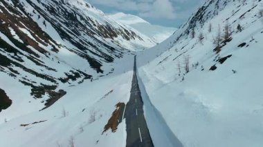 Kar duvarları olan boş dağ yolunun insansız hava aracı kış mevsiminde yoğun kar yağışı sonrasında koridor oluşturuyor. Alplerdeki güzel ve sinematik dağ vadisi, baharda dağ geçidi temizlendi ve açıldı.