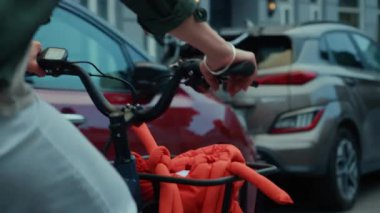 Bir kargo elektrikli bisiklet sepetine, gidona, vites koluna, şık turuncu çantalı sepete yakın durun. Her gün gidip gelen bir kadın.