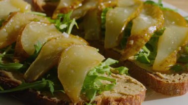 Humus, roka ve karamelize armutla kaplı lezzetli bir buğday ekmeği hazırlama ve servis etme süreci.. 