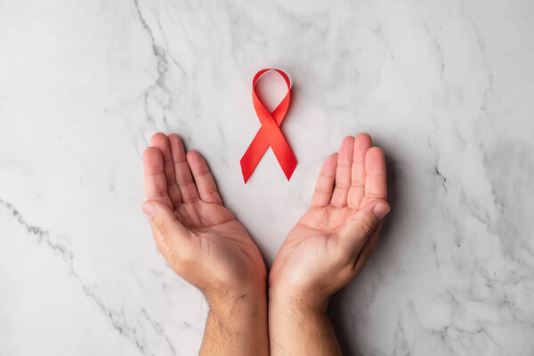 Открытые руки мужчины с красной ленточкой в поддержку Всемирного дня борьбы со СПИДом. Понимание с людьми, инфицированными ВИЧ