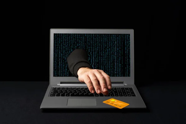 A cybercriminal reaching through a laptop to steal an online shopper\'s credit card. Internet scams