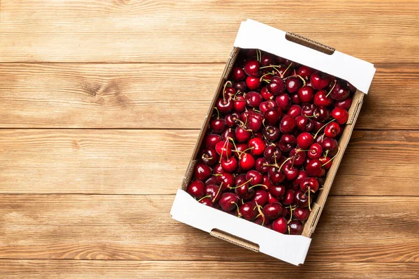 纸板箱 在木制桌子上装满了红色的樱桃 樱桃的销售 健康的浆果 — 图库照片
