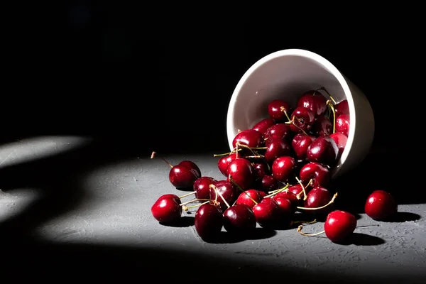碗里装满了深色底色的红色樱桃 倾覆杯洒出富饶健康的樱桃 — 图库照片