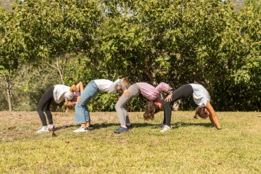 Parkta akrobatik egzersizler yapan dört kız. Çocuklar dışarıda oynuyor ve jimnastik aktivitelerine katılıyorlar. Gençlikte sağlıklı yaşam ve beslenme