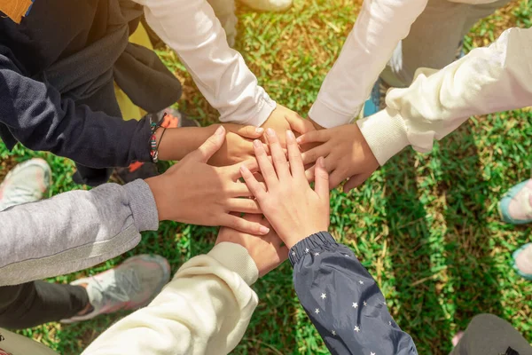 A group of children\'s hands joined at the center. Cooperation and camaraderie among friends. Unity and collaboration strengthen a team. Together for a common cause