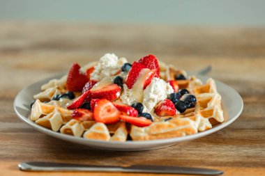 Üzerine çilek, yaban mersini ve taze krema konmuş Altın Belçika Waffle 'ları. Her lokmada ağız sulandıran bir lezzet özel bir kahvaltı ya da kahvaltı için.