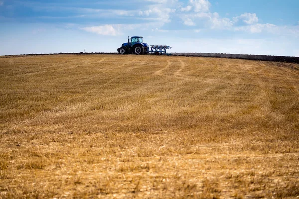 一辆配有可复耕犁和剥皮辊的现代蓝色拖拉机正在犁田 春天的谷物刚刚收获 乌克兰中部仲夏 — 图库照片