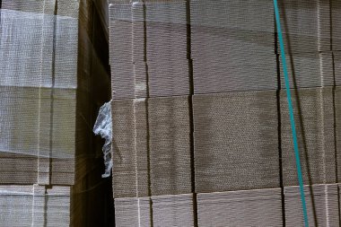Karton kutuları katlıyorum. Delik deşik olmuş karton çarşaflar paletlerin üzerinde bir yığın. Endüstriyel üretimde bitmiş ürünlerin ambalajı.
