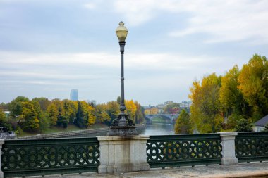 İtalya 'nın Torino kentinde Ponte Isabella' da, Po Nehri 'ne ve sonbahar yapraklarına bakan bir elektrik direği bulunuyor. Köprünün zarif tasarımının bir ayrıntısı..