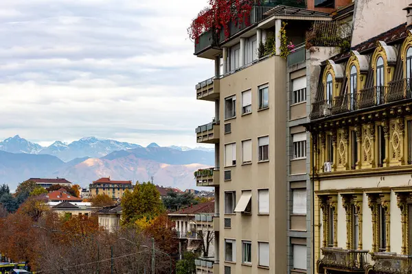 İtalya, Torino 'daki binalar, karla kaplı Alpler' in manzaralı arka planı. Dağ manzaralı şehir manzarası.