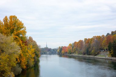 Renkli sonbahar yaprakları İtalya 'nın Torino kentindeki Po Nehri' nin kıyısında yer alır. Canlı ağaçların yansımaları suda parıldıyor..