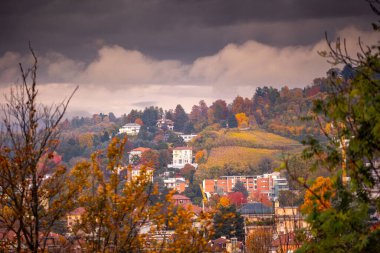 İtalya, Torino 'daki tepe manzarası sonbahar renkleriyle dolup taşıyor. Evler bulutlu bir gökyüzünün altındaki manzarayı noktalar..