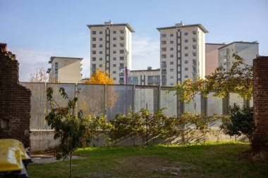 İtalya 'nın Torino kentinin aksine, modern apartmanlar eski bir tuğla duvarın ve sonbahar yeşilliğinin arkasında görülüyor. Farklı dönemleri gösteren şehir manzarası.