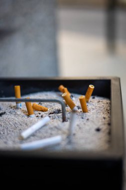 Kumda söndürülmüş sigara izmaritleriyle dolu bir kül tablası..
