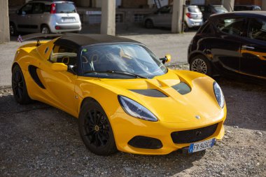 Torino, İtalya - 08 Kasım 2021: Siyah tekerli parlak sarı bir Lotus Elise spor arabası ve dışarıda çakıllı bir yüzeye park edilmiş bir spoiler.